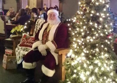 Santa Dan Next To Lit Up Christmas Tree