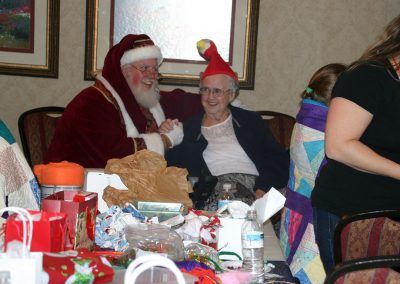 Santa Dan Holding Elderly Lady's Hand While Both Smile